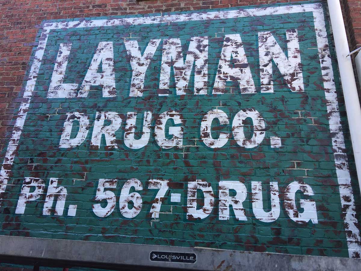 A sign on a brick wall that says ' layman drug co ' on it