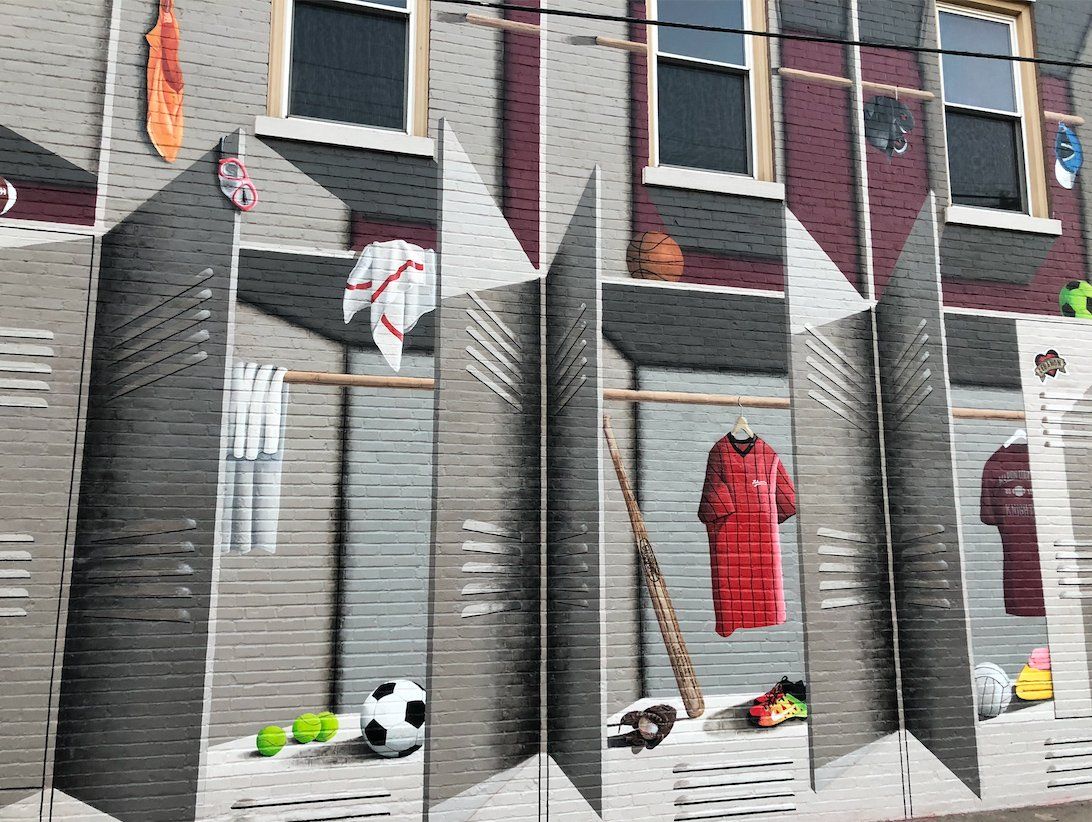 A mural on the side of a building shows lockers and clothes