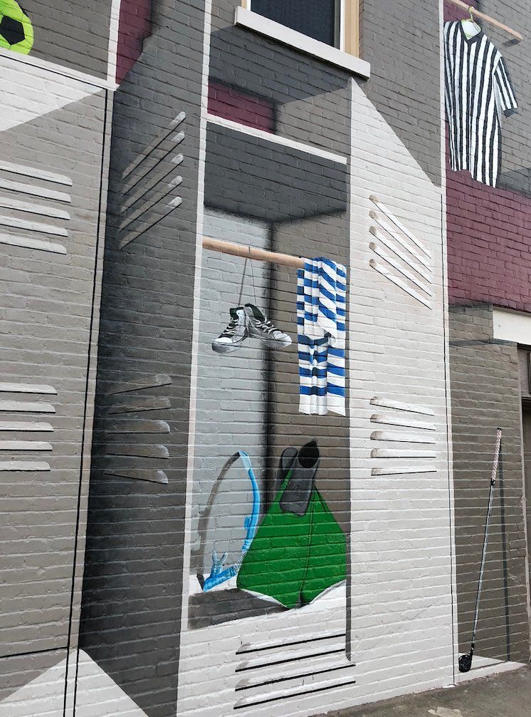 A mural on the side of a building shows a locker with clothes in it.