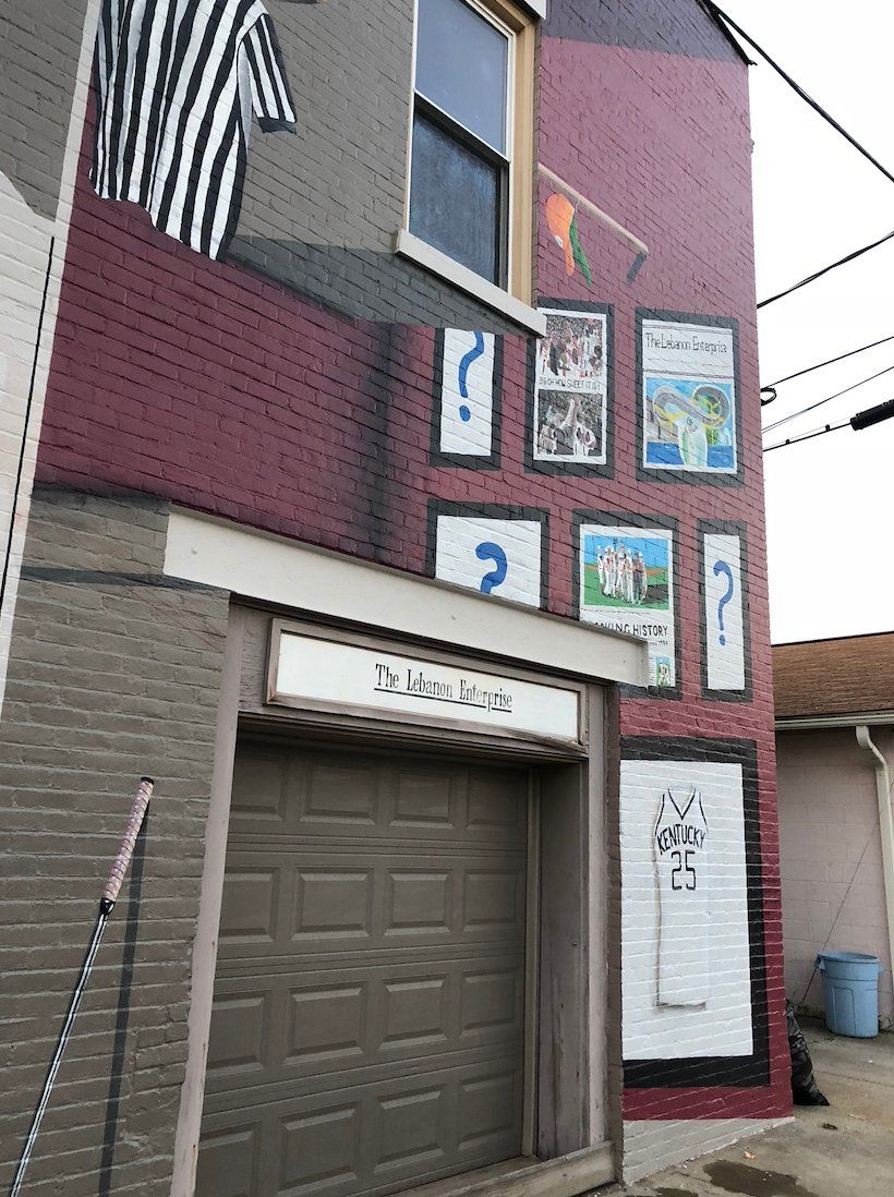 A brick building with a garage door and a mural on the side.