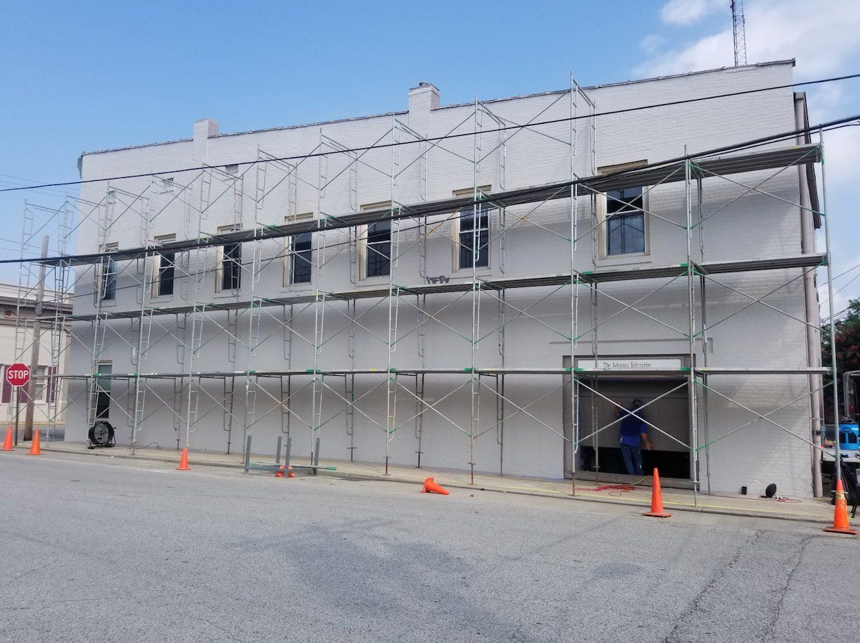 A building with scaffolding around it is being painted white