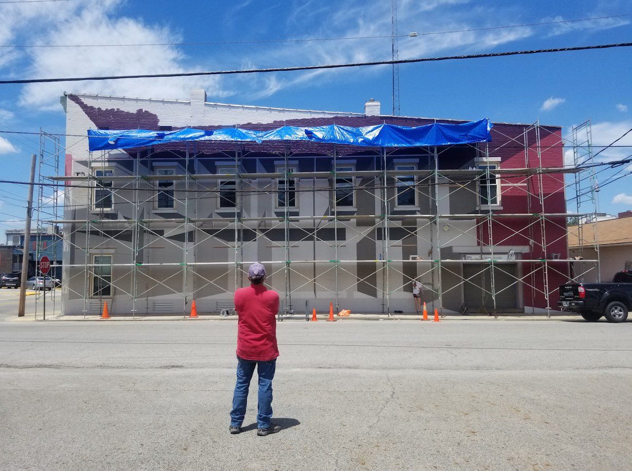 A man in a red shirt is standing in front of a building under construction