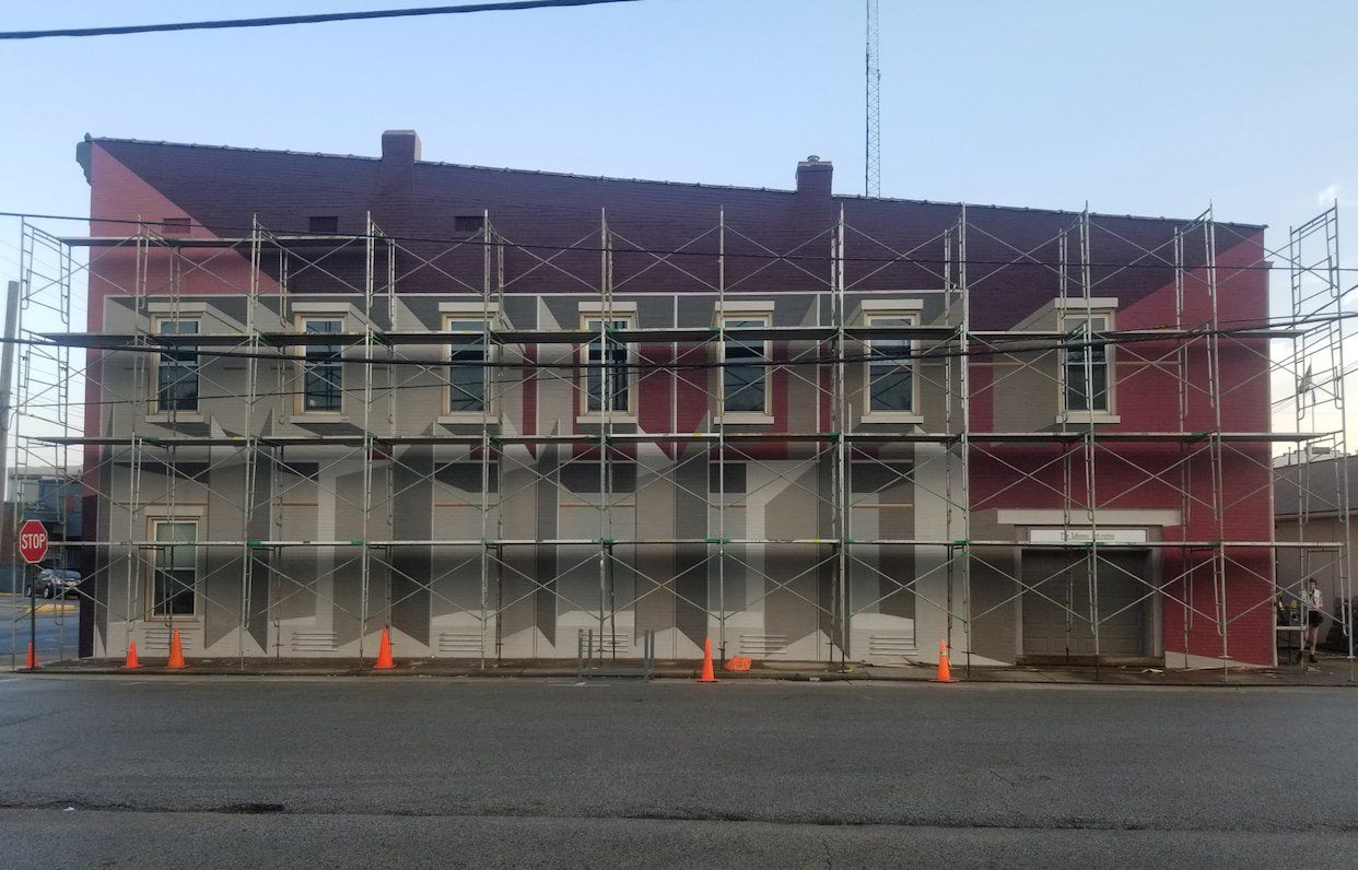 A red building with scaffolding around it is under construction.