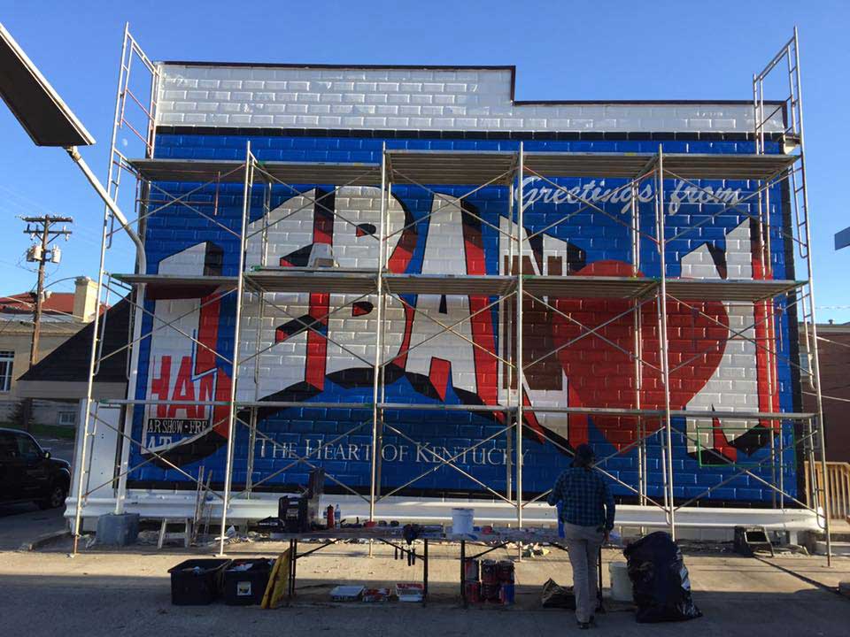 A mural is being painted on the side of a building