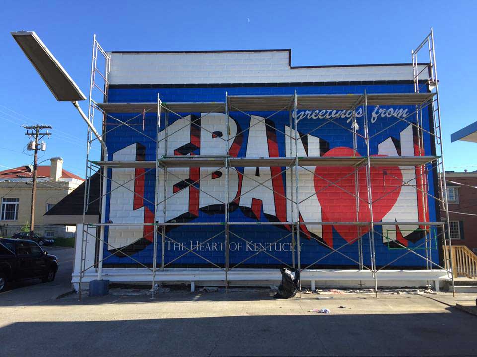 A mural is being painted on the side of a building