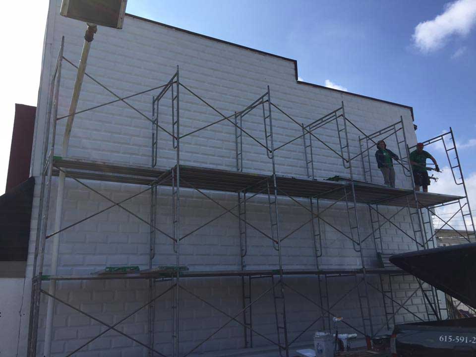 Two men are standing on scaffolding on the side of a building.