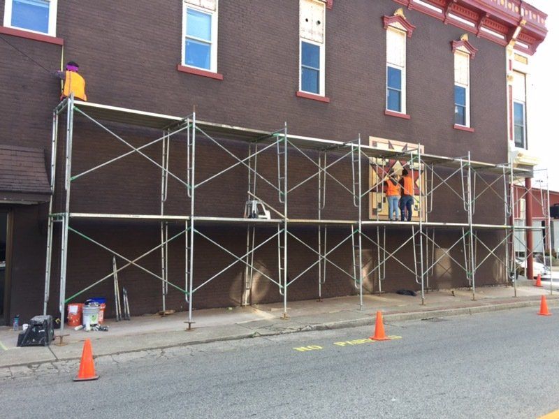 A group of people are standing on scaffolding in front of a building