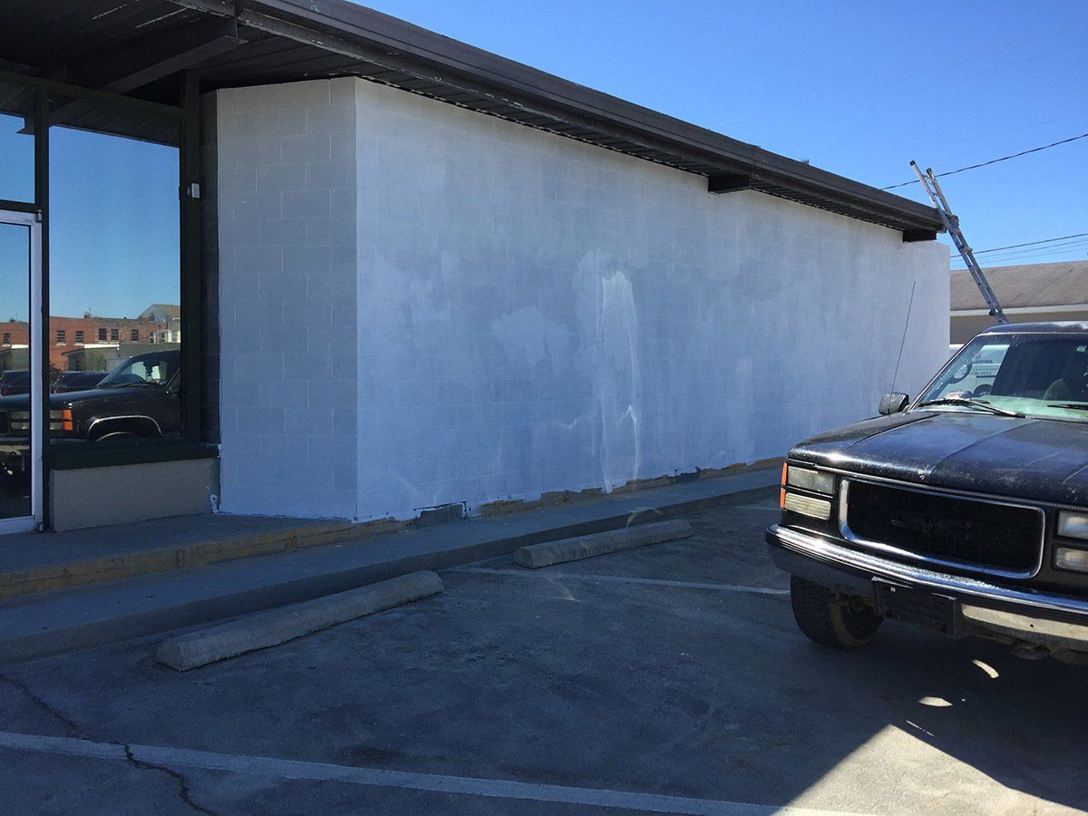 A black truck is parked in front of a white building