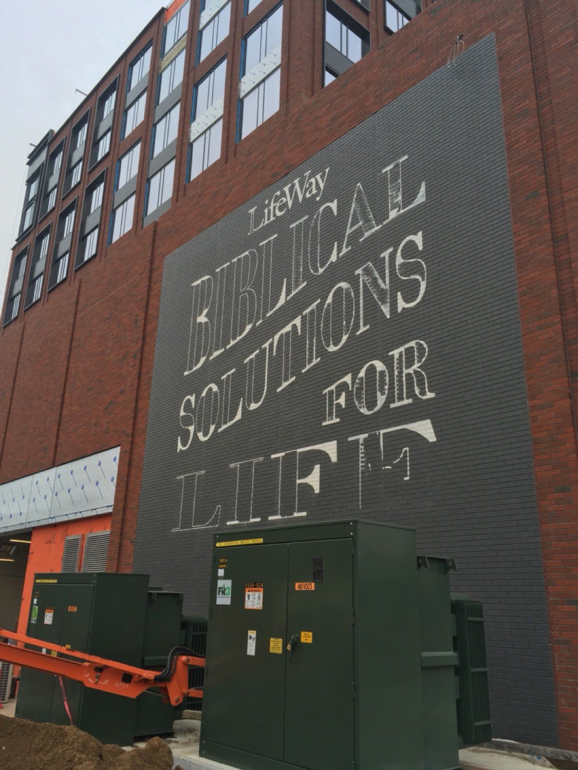 A large sign on the side of a building says biblical solutions for lifts