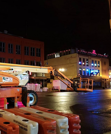 A construction vehicle is parked in front of a building at night
