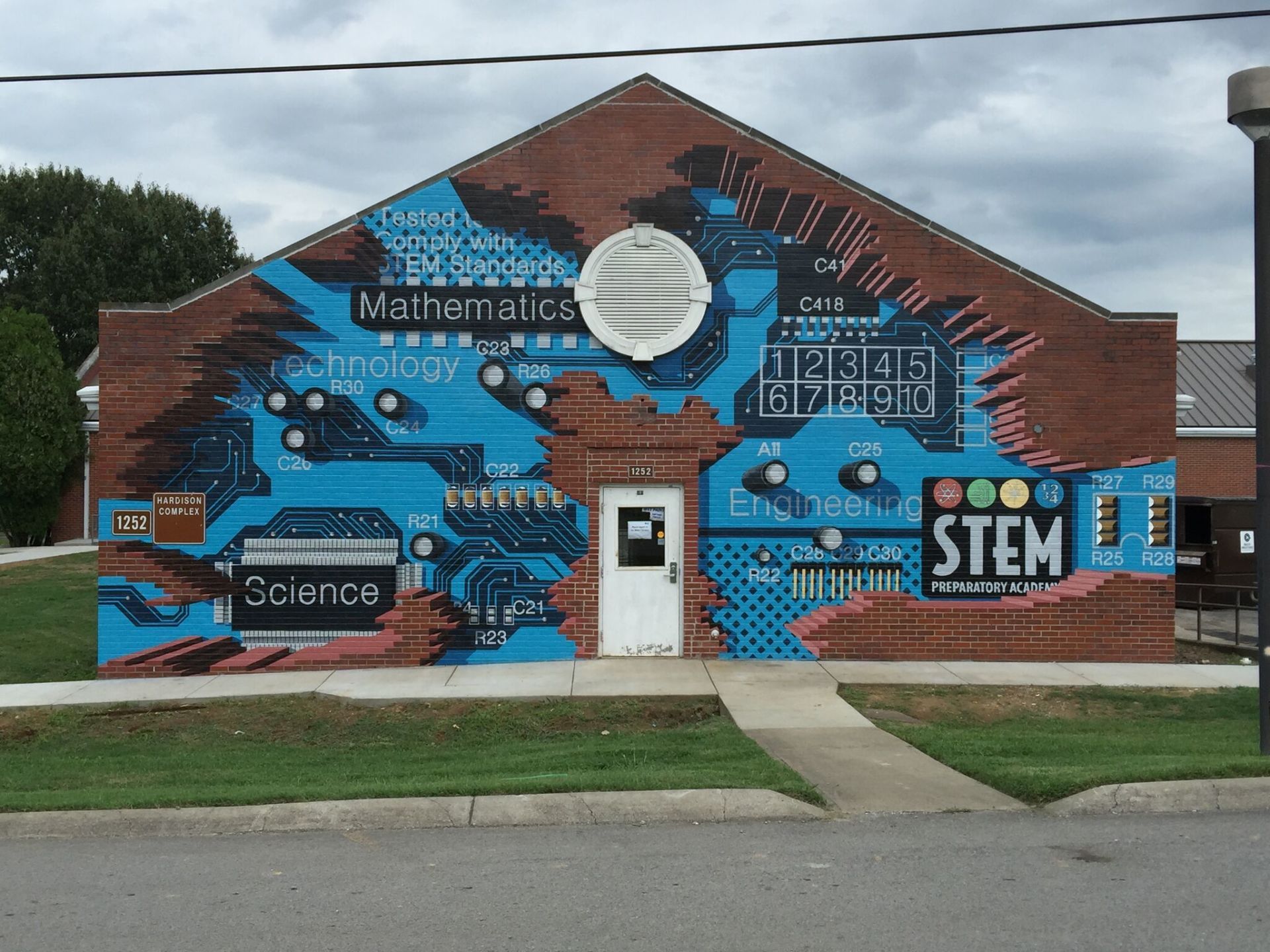A brick building with a mural on the side that says stem