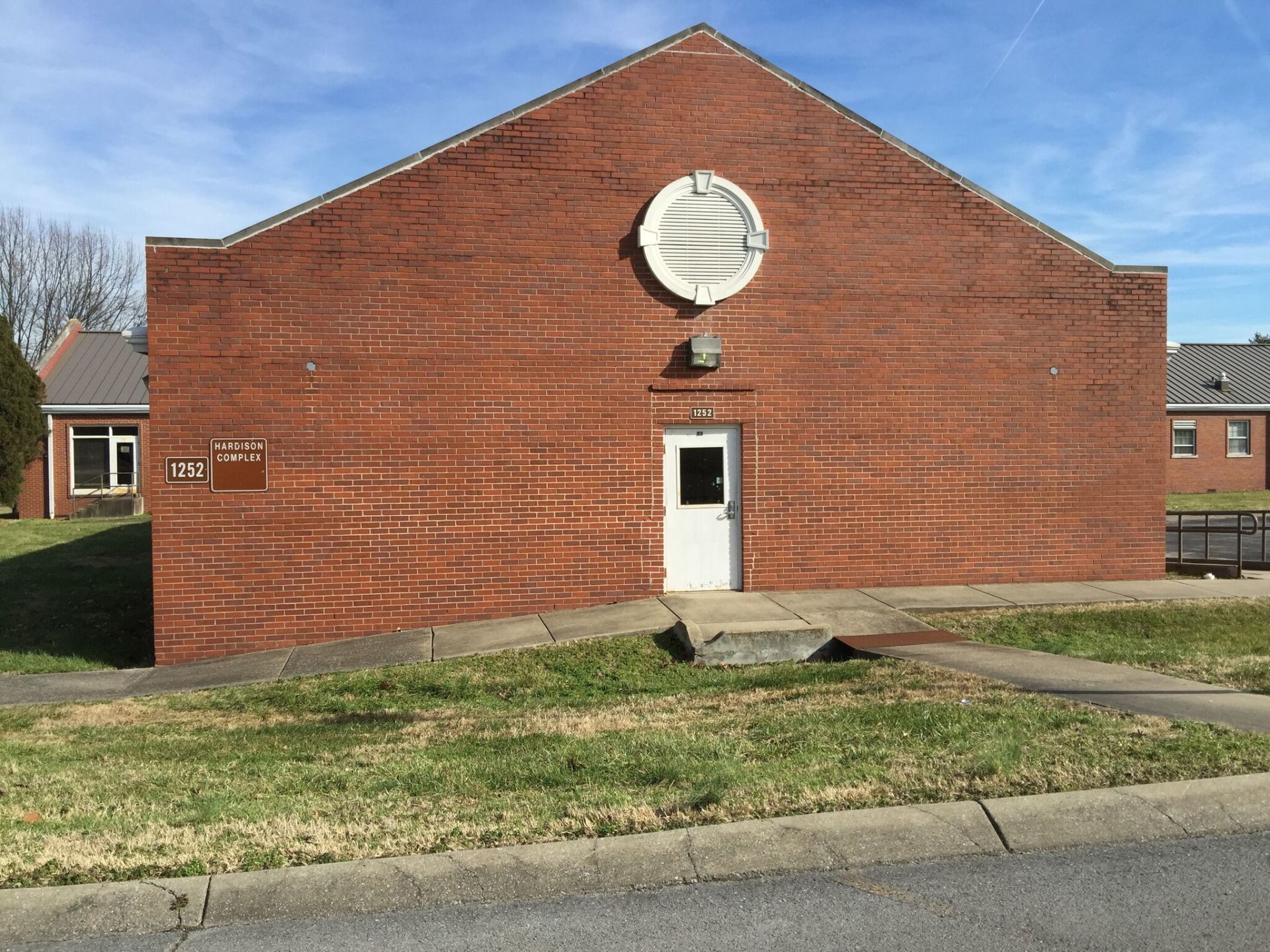 A large brick building with a white door and a circular window on the side.