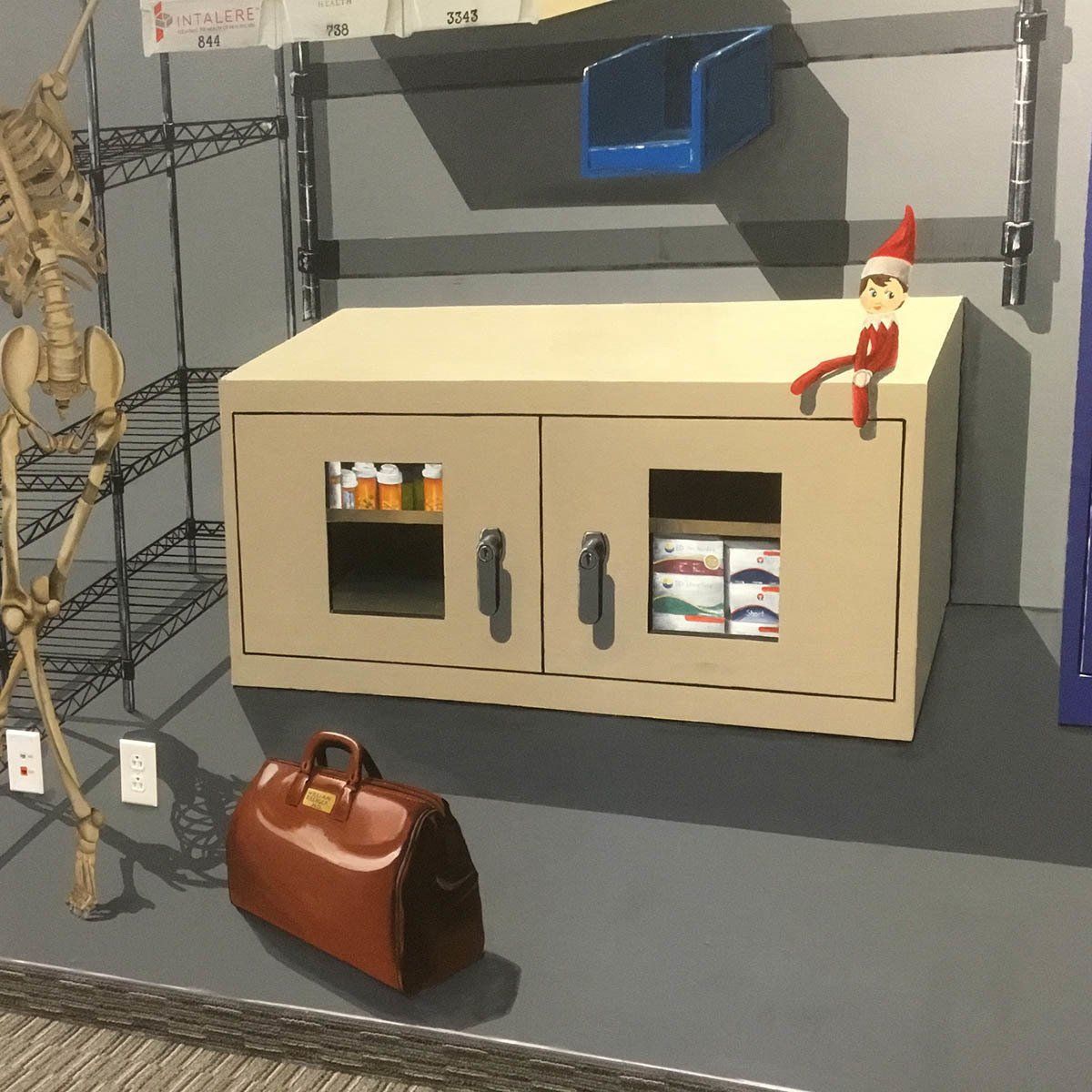 An elf on the shelf is sitting on a cabinet
