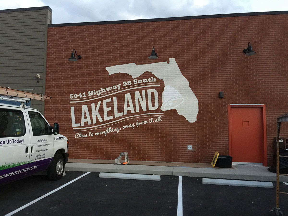 A white van is parked in front of a brick building that says lakeland.