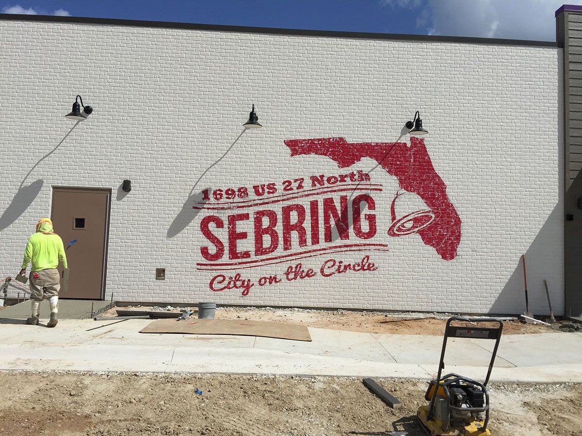 A man is painting a mural on the side of a building.