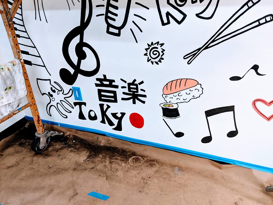 A white wall with drawings on it and the word tokyo on it
