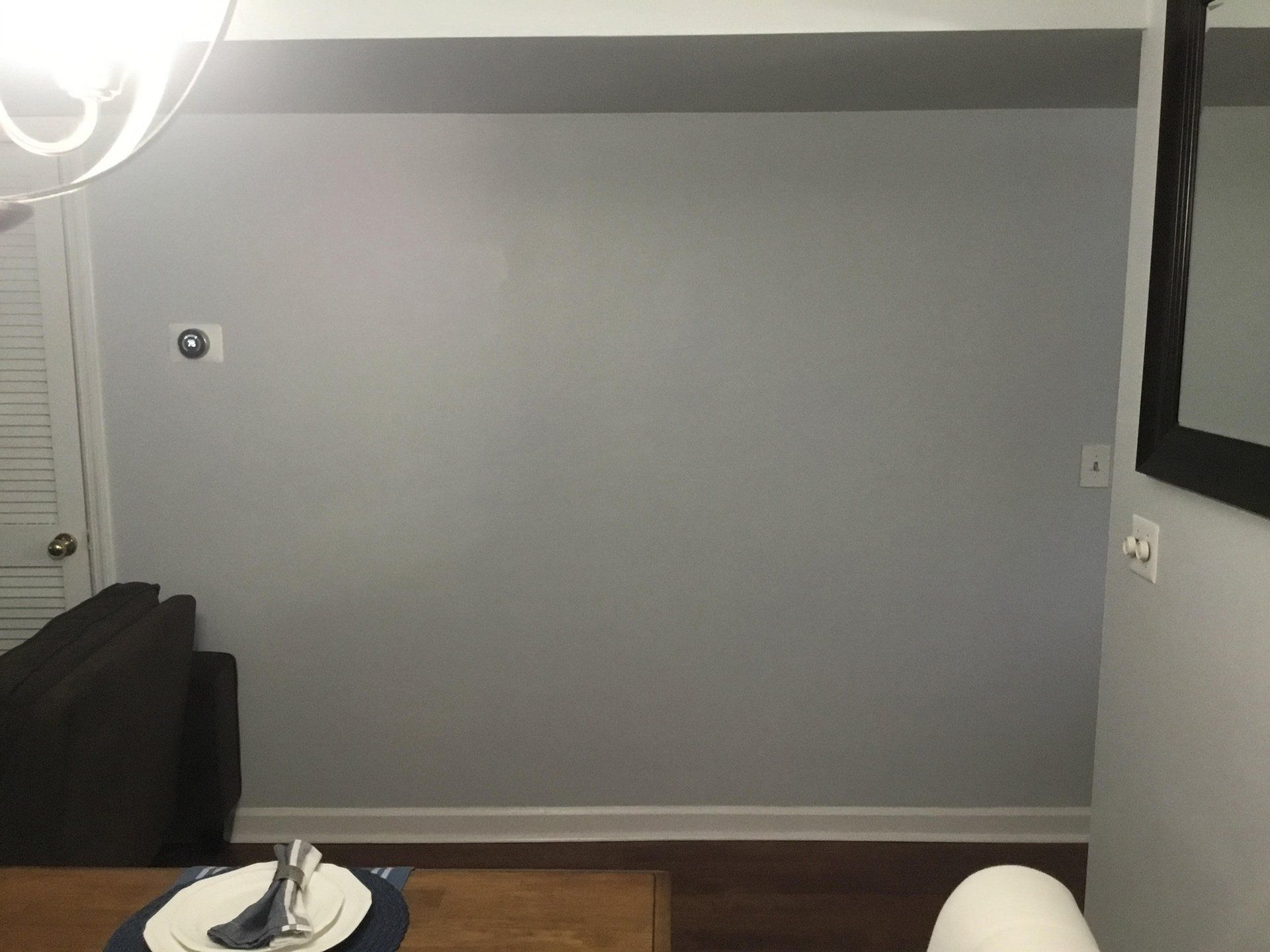 A dining room with a table and chairs and a gray wall.