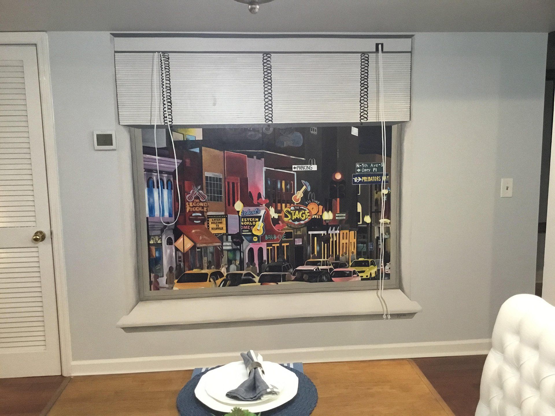 A living room with a painting on the wall above a window