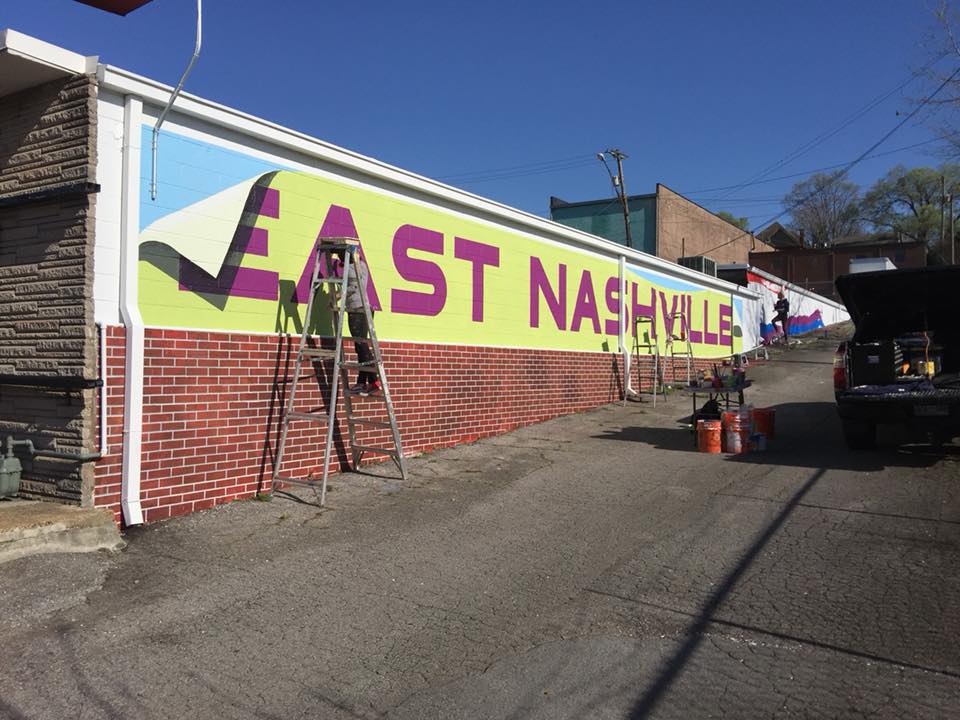 A mural is being painted on the side of a building that says east nashville
