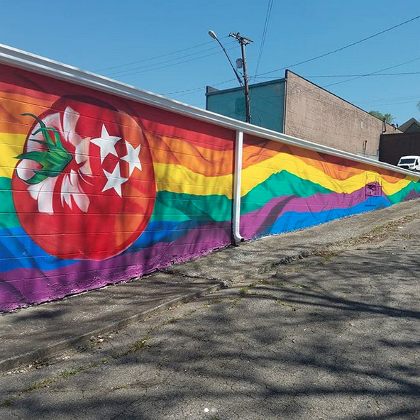 A rainbow colored wall with a tomato on it