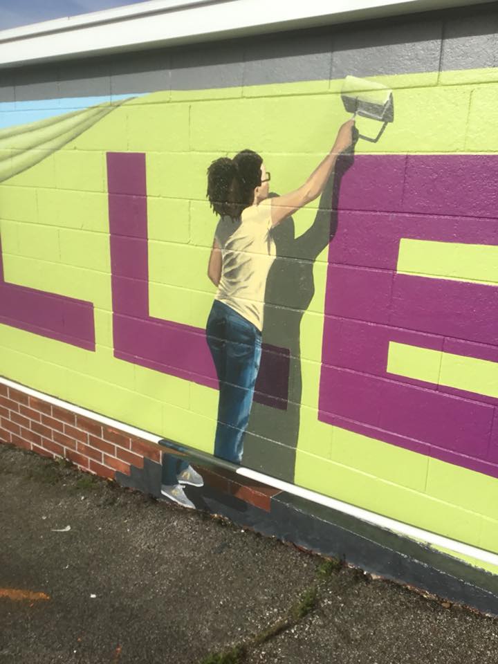 A woman is painting the word lee on a wall