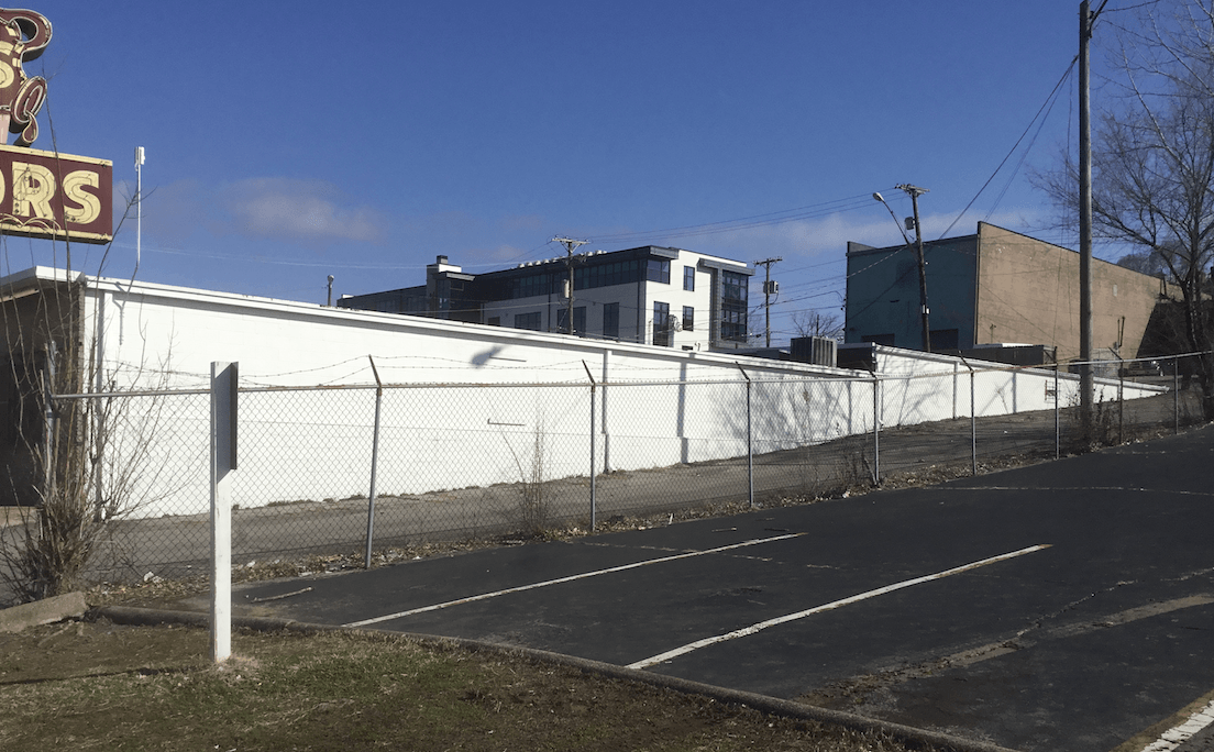 A white building with a sign that says rs is behind a chain link fence next to a road.