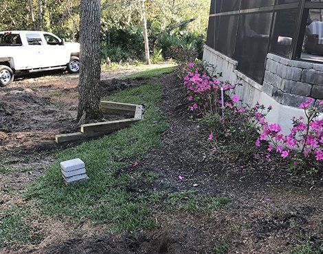 Side yard with tree and azalea bushes; a truck is parked nearby.