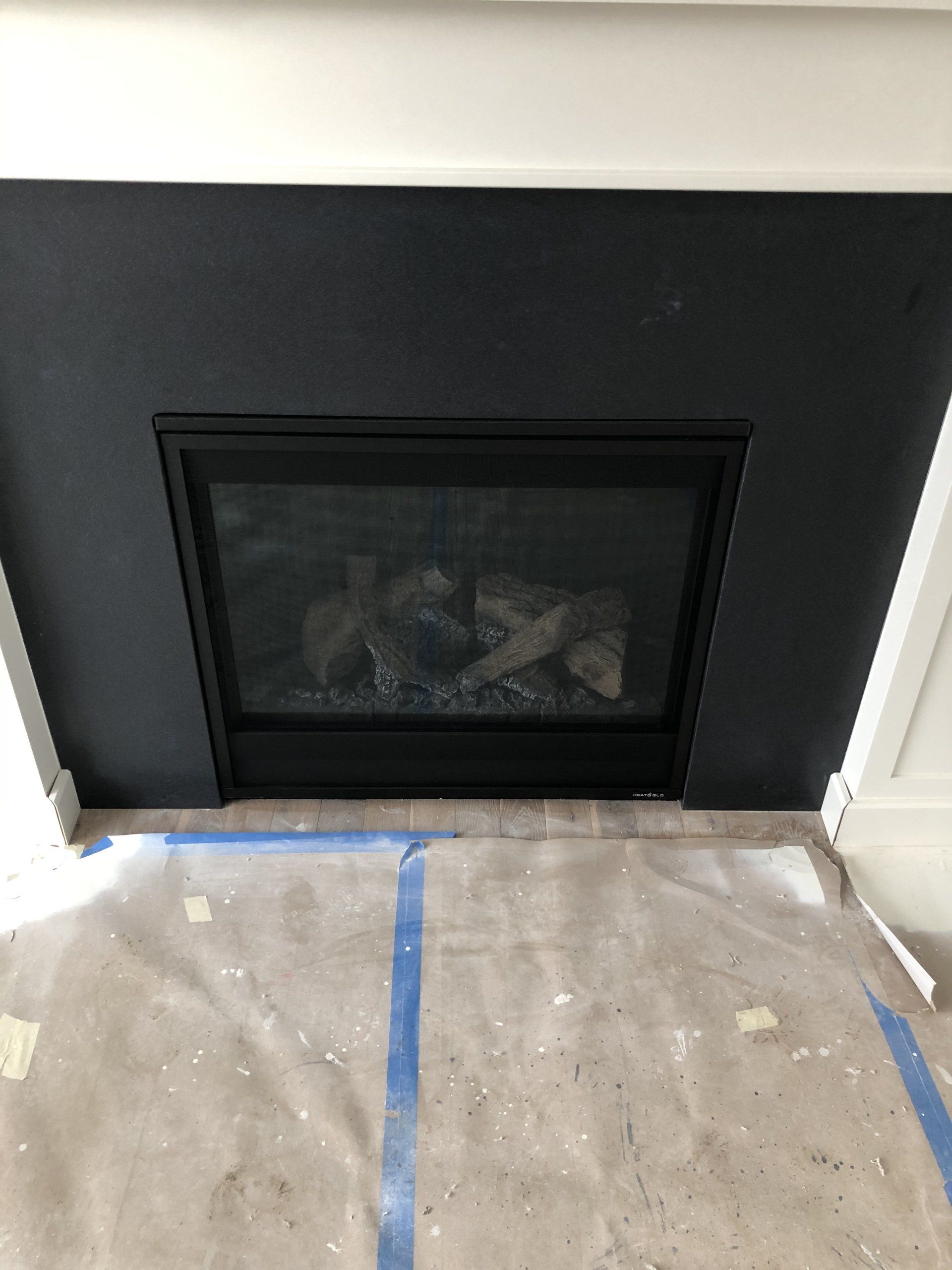 A fireplace with a glass door is sitting on top of a concrete floor.