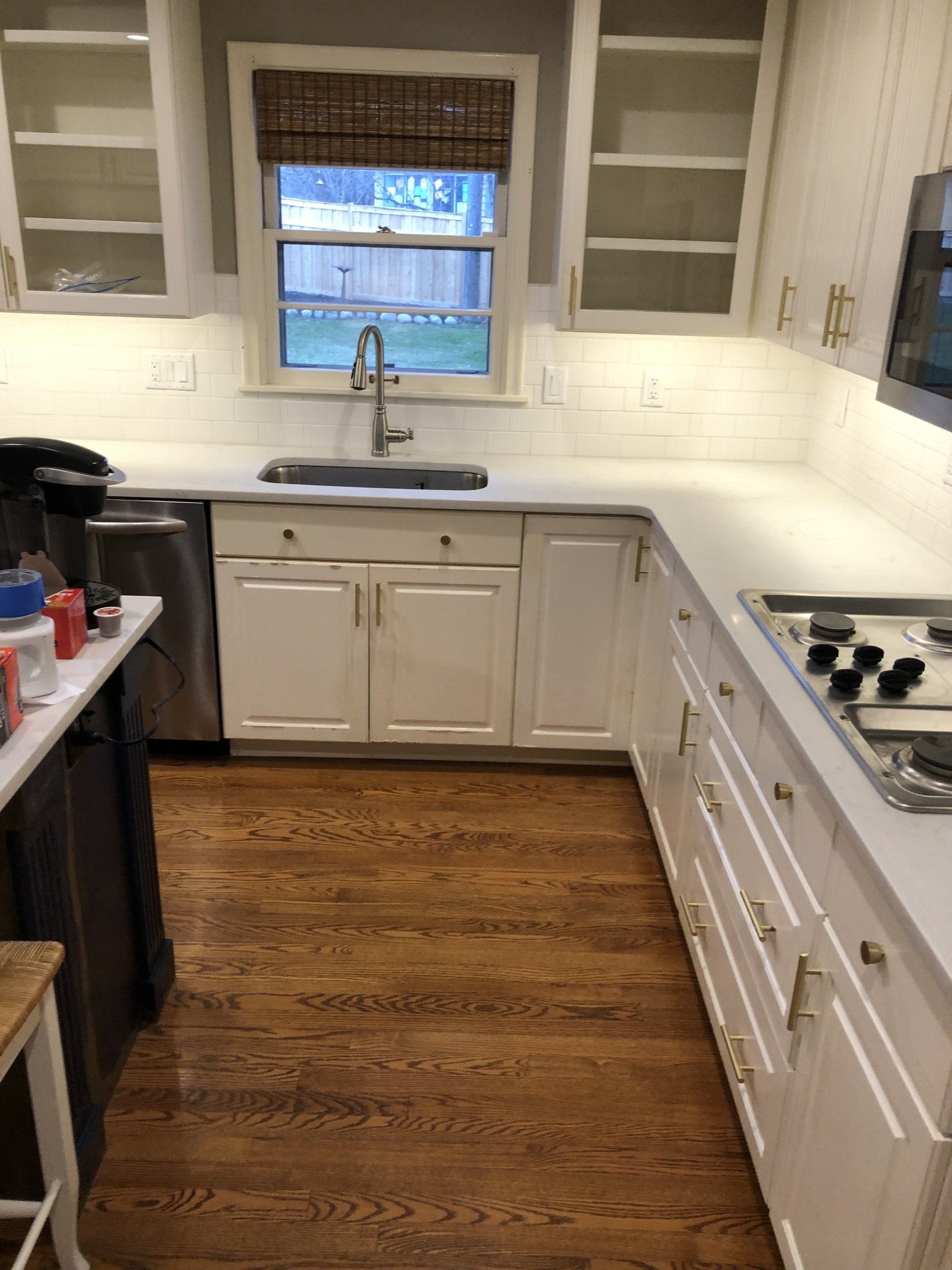Kitchen remodel | white cabinets , stainless steel appliances , hardwood floors and a window.