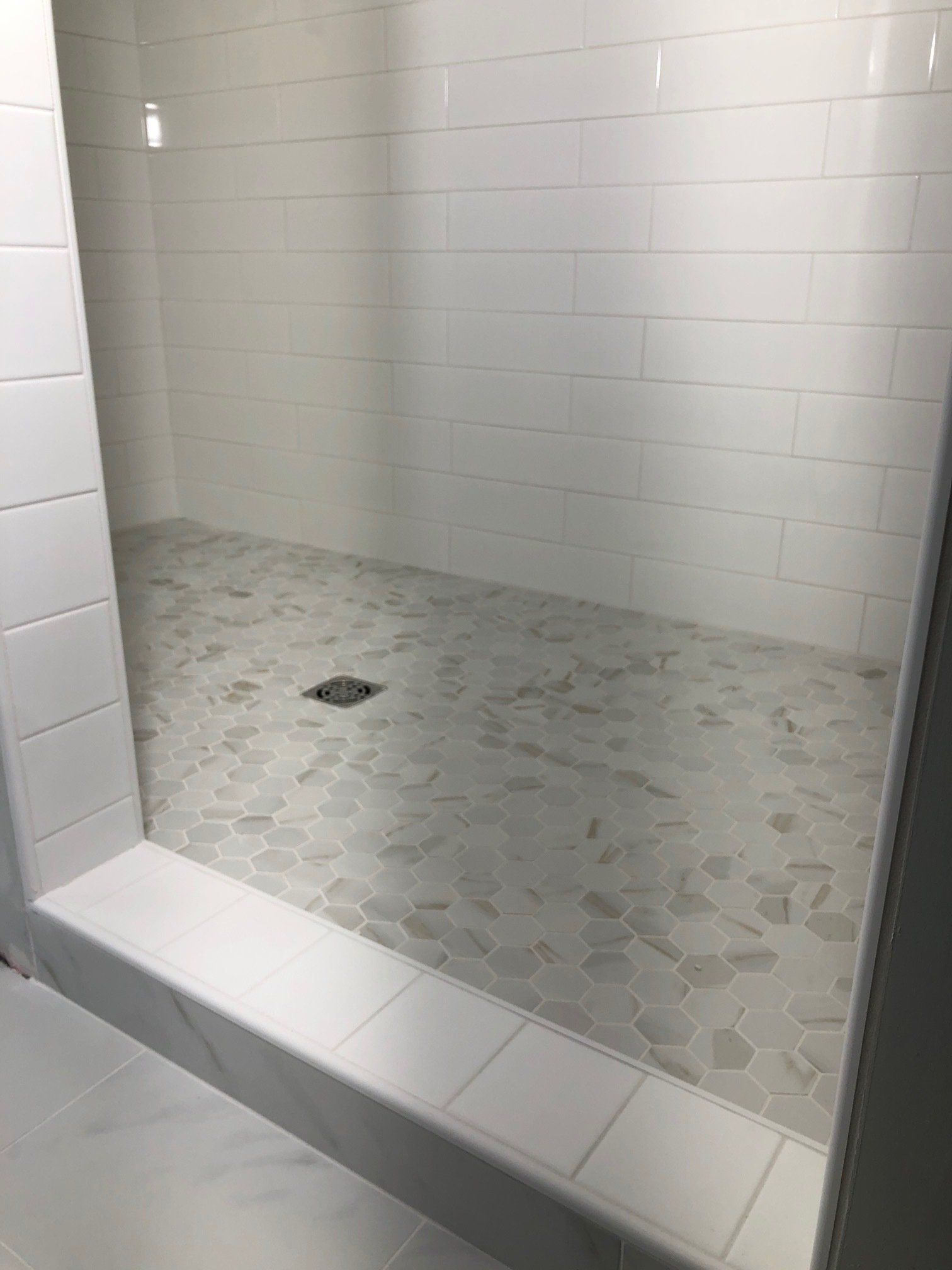 Bathtub to shower conversion | A bathroom with white tiles and a walk in shower.