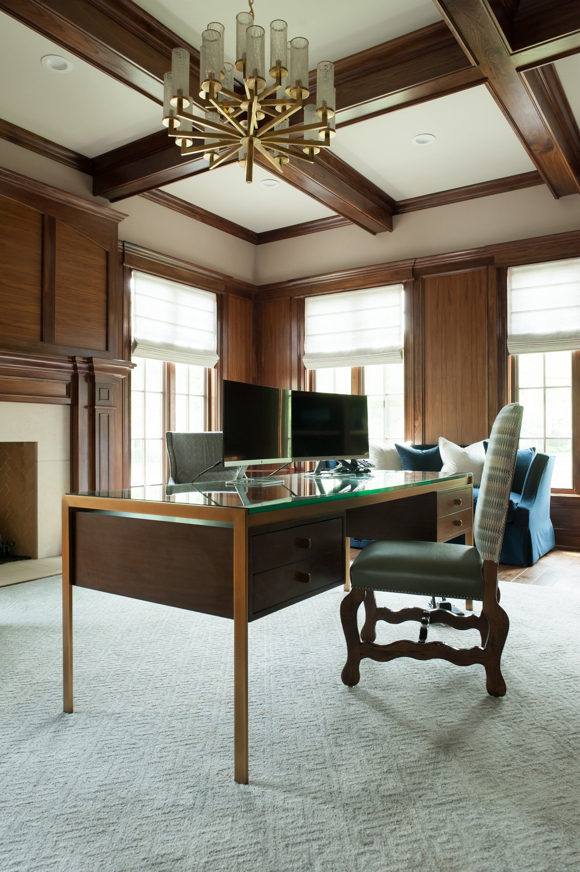 A home office with a desk and chair and a chandelier hanging from the ceiling.