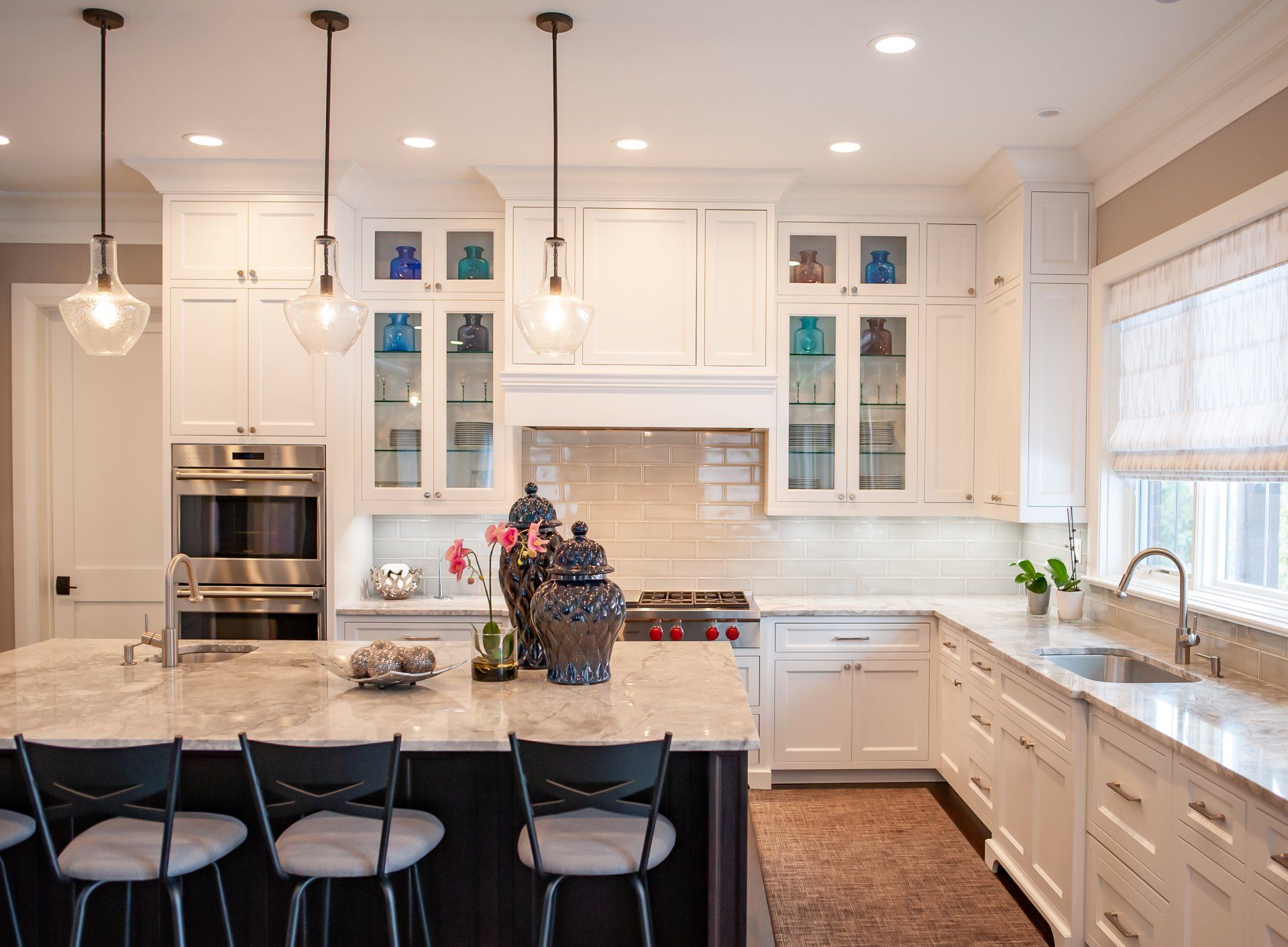 A kitchen with white cabinets , stainless steel appliances , a sink , and a large island.