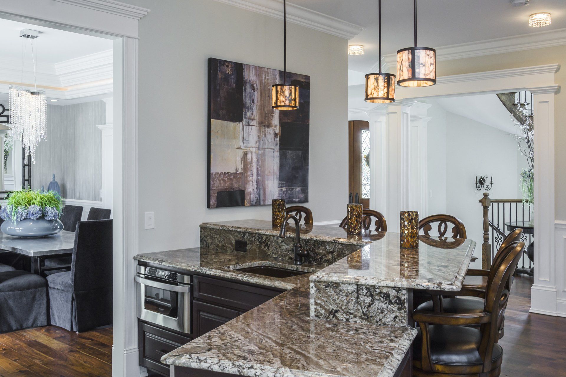 A kitchen with granite counter tops and a dining room in the background.