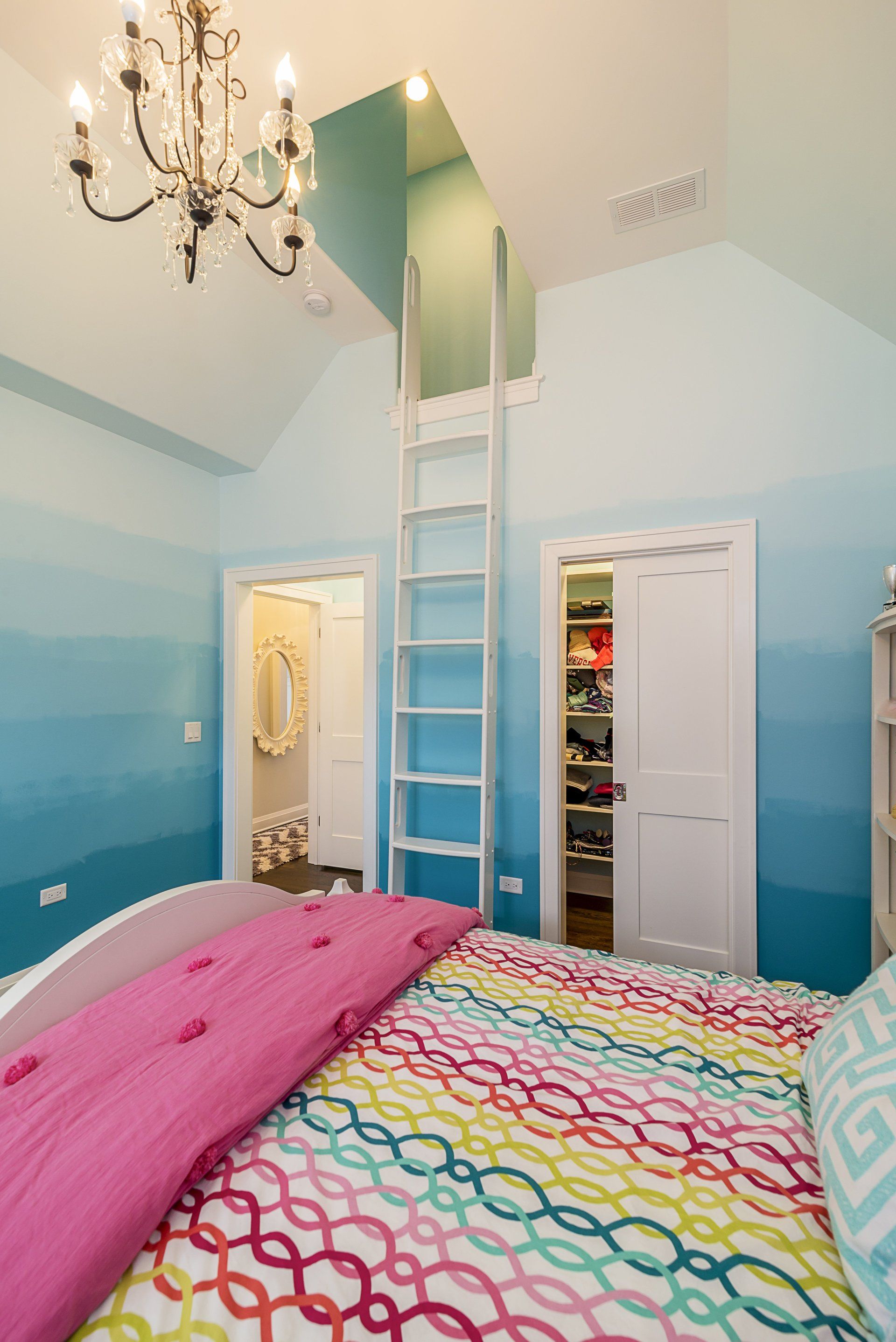 A bedroom with a bed and a ladder leading to a loft.