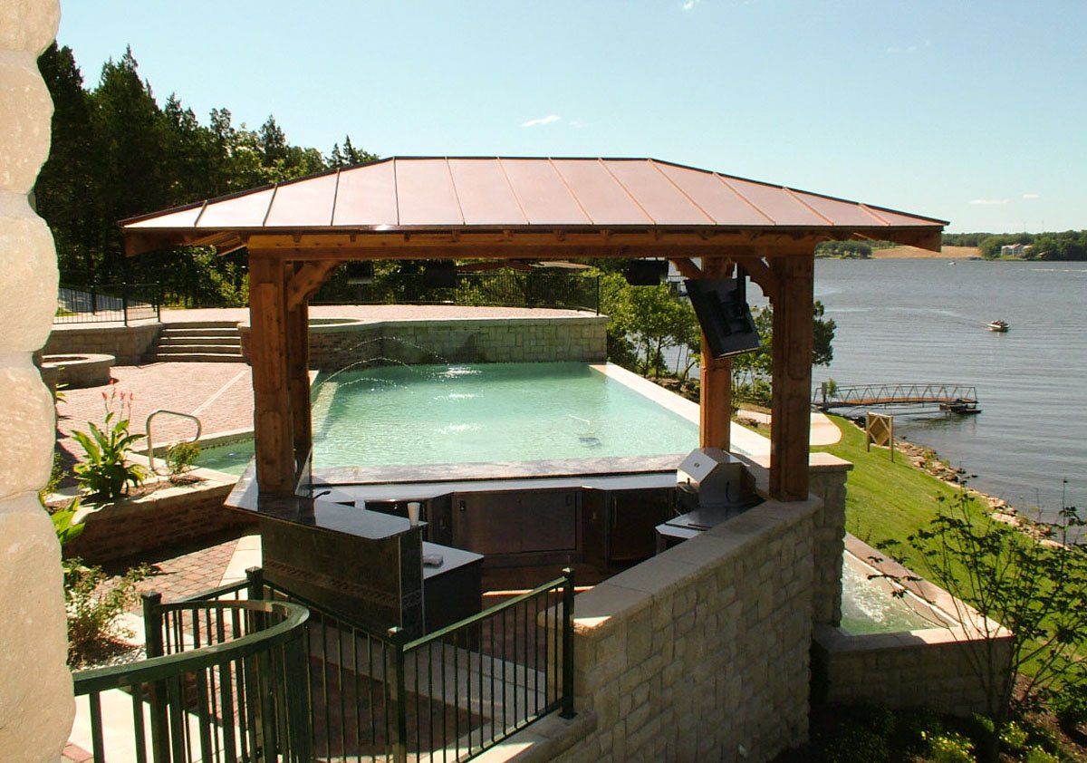 A gazebo overlooking a swimming pool and a lake
