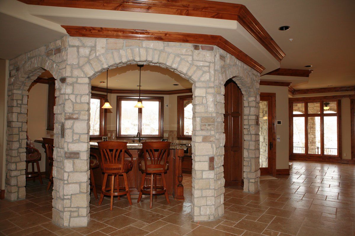 A room with a stone archway leading to a kitchen