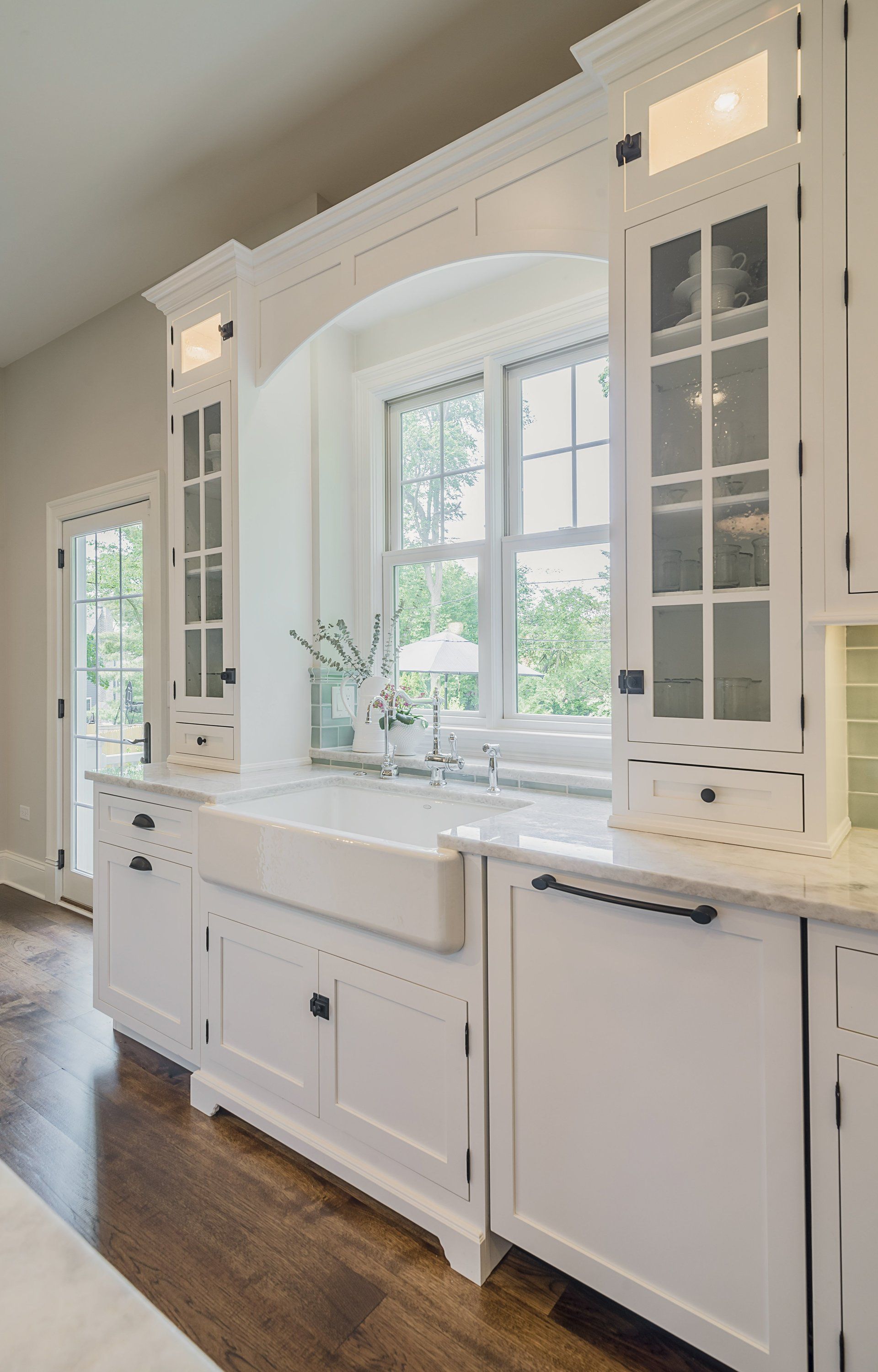 A kitchen with white cabinets , a sink , and a window.