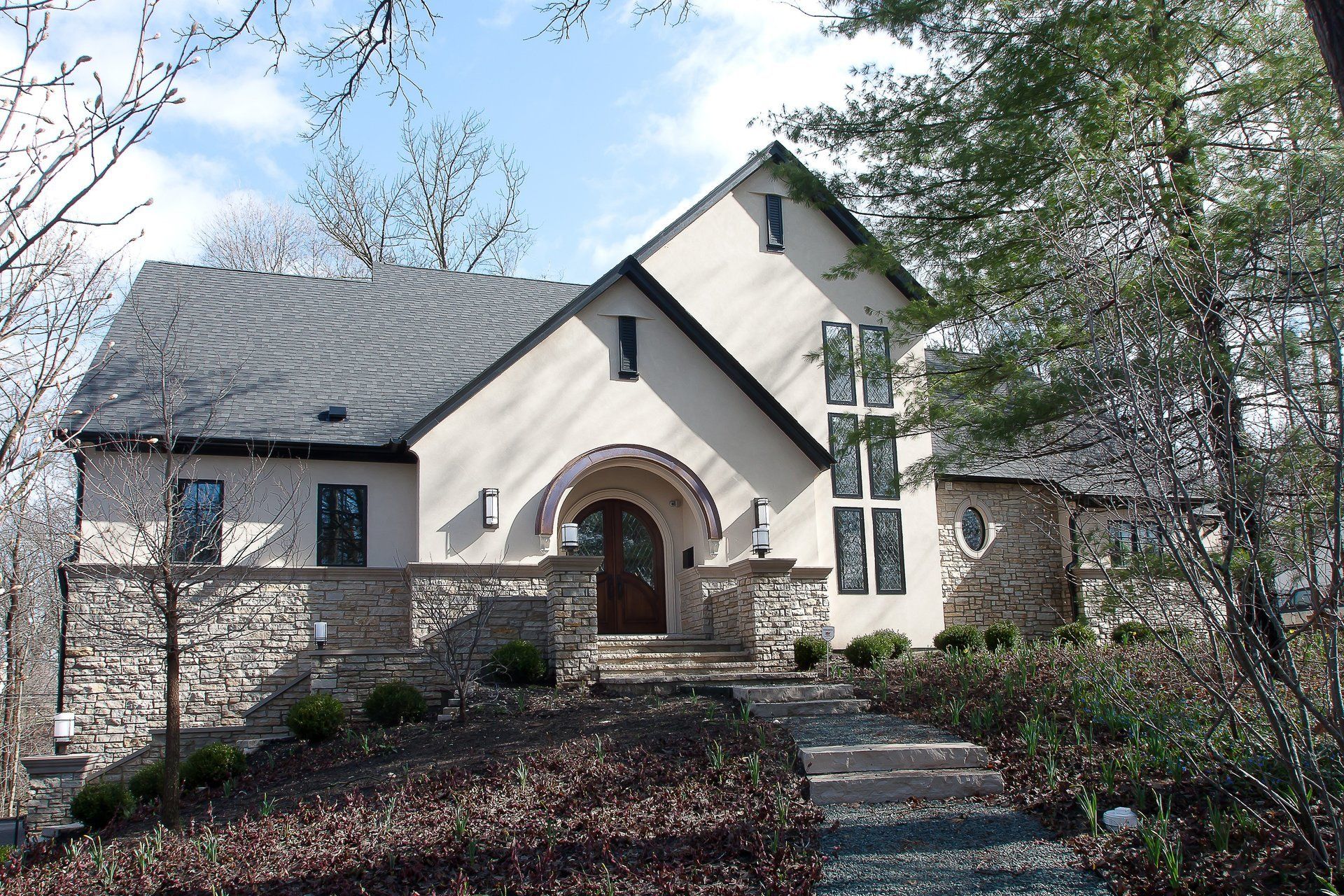 A large white house with a black roof is surrounded by trees