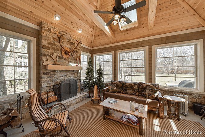A living room with a couch , chairs , a fireplace and a ceiling fan.
