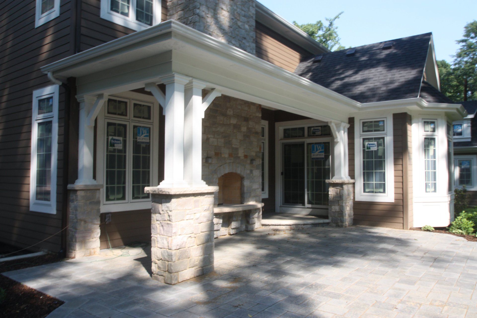 A brown and white house with a porch and a fireplace