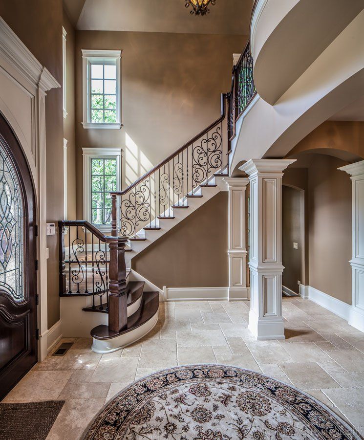 A hallway with a staircase and a rug in the middle