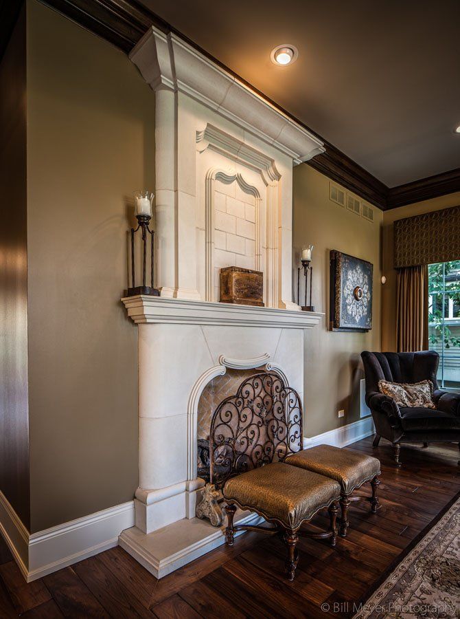 A living room with a fireplace , chairs and ottomans.