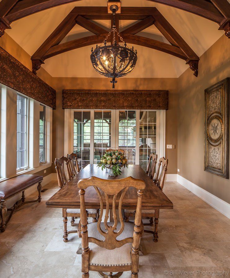 A dining room with a table and chairs and a clock on the wall