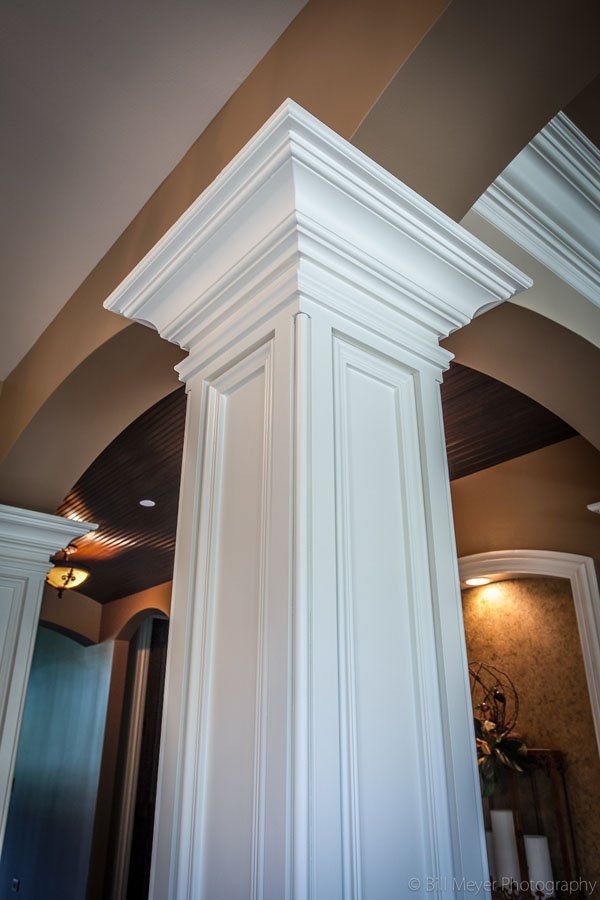 A white column in a room with a brown ceiling.