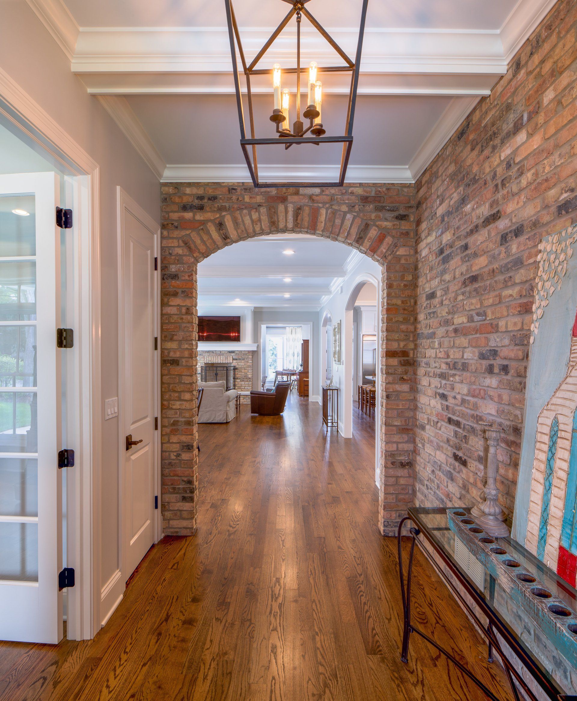 A hallway with a brick wall and a chandelier hanging from the ceiling