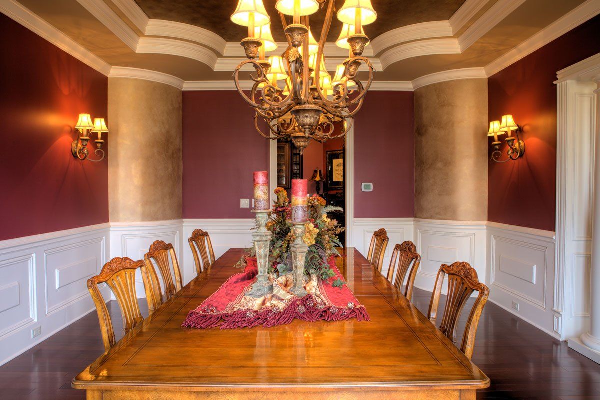 A dining room with a long table and chairs and a chandelier.
