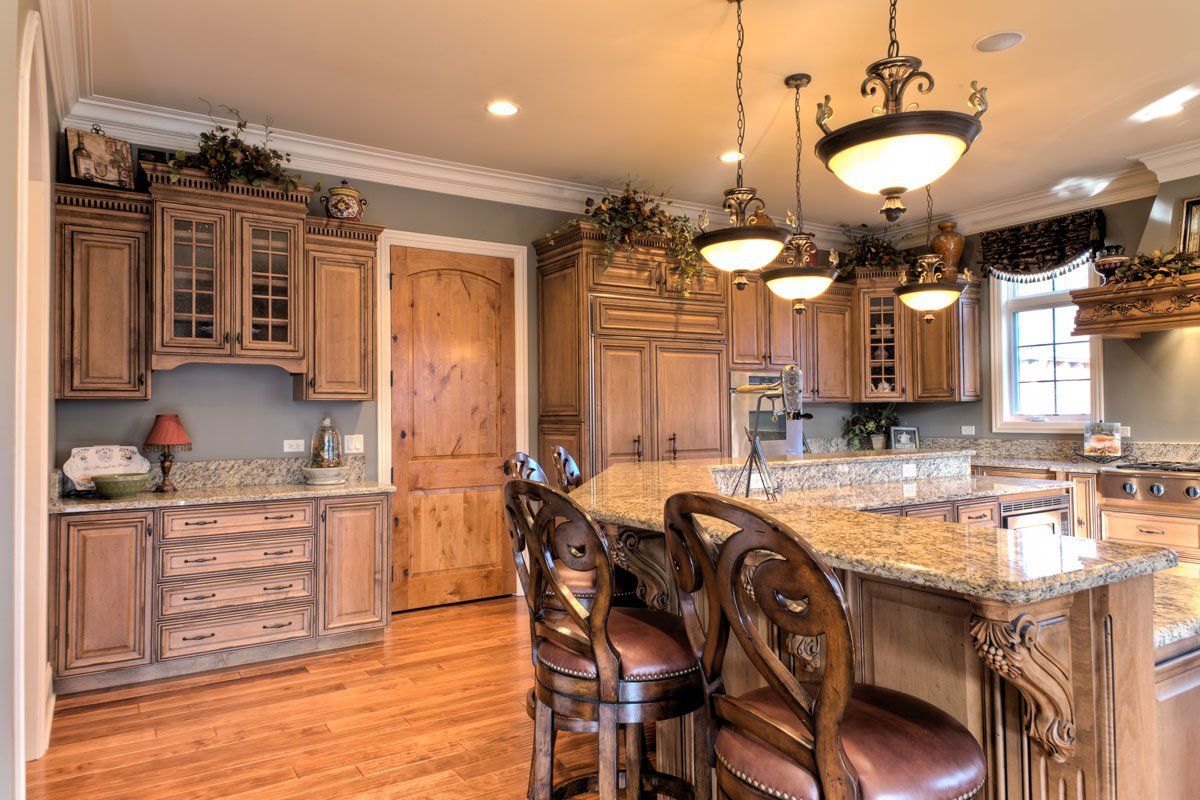 A kitchen with wooden cabinets , granite counter tops , and stools.
