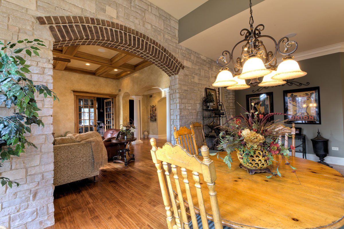 A dining room with a wooden table and chairs and a chandelier.