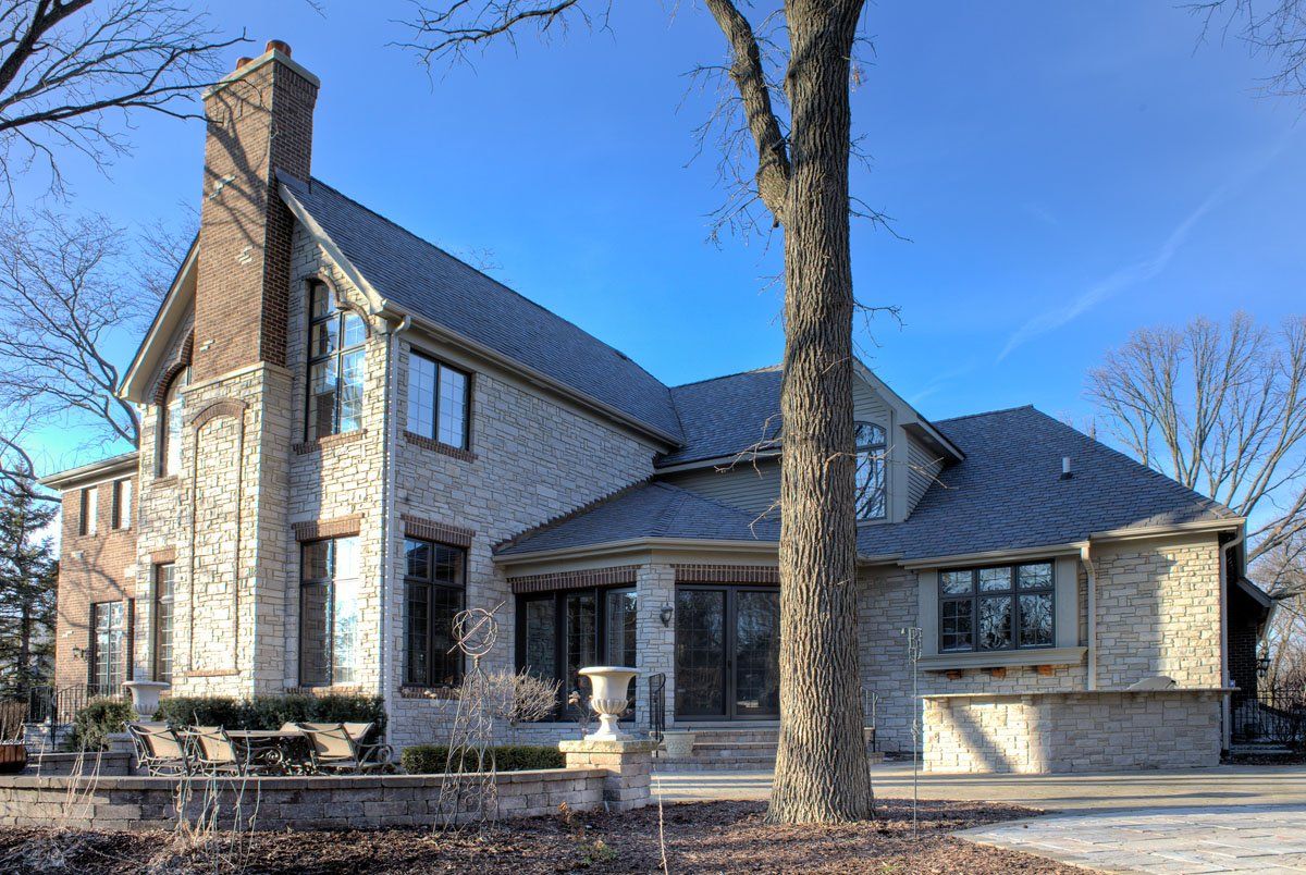 A large brick house with a tree in front of it on a sunny day.