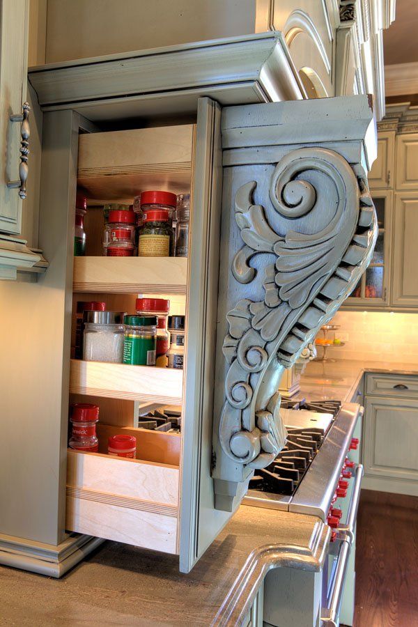 A kitchen with a pull out spice rack and a stove.